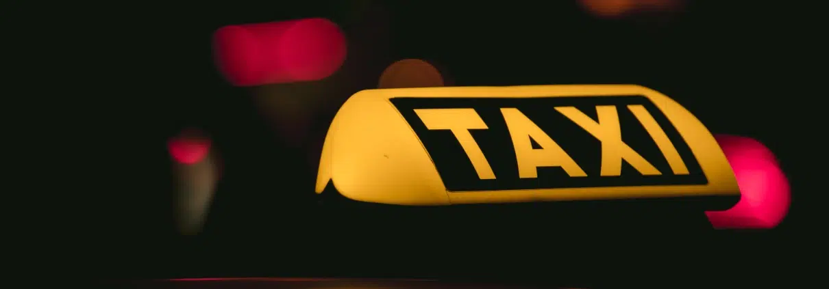 Chauffeur à côté de son véhicule équipé d’un lumineux taxi