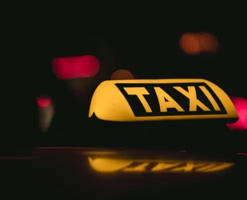 Chauffeur à côté de son véhicule équipé d’un lumineux taxi