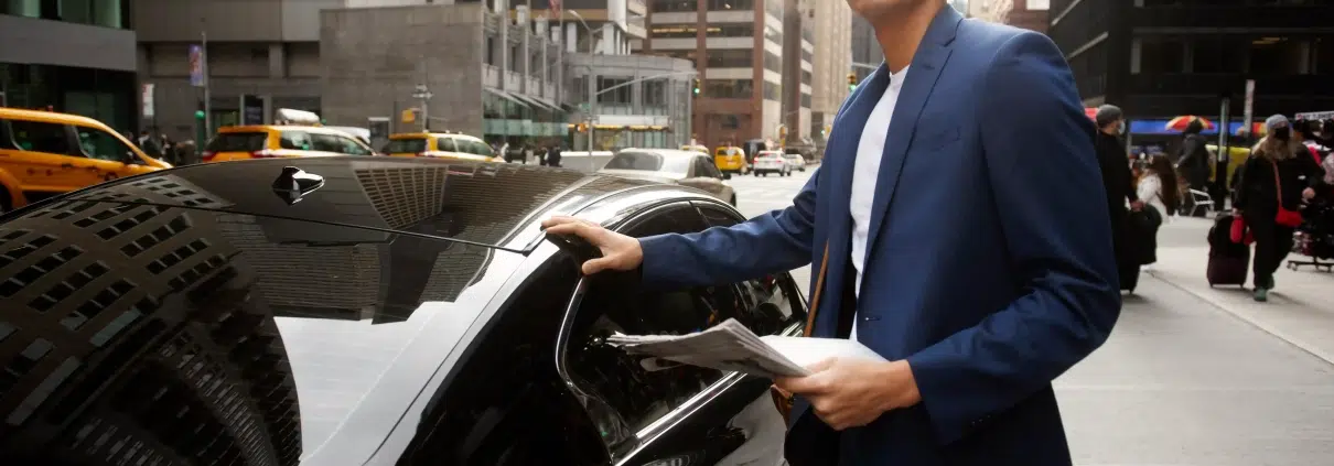 Chauffeur de taxi aidant un client à porter sa valise près du véhicule
